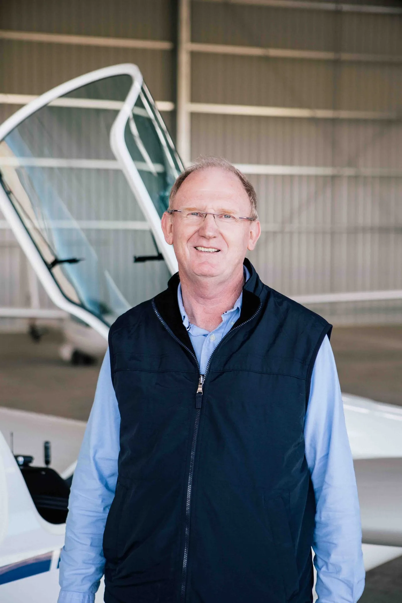 Damien O'Reilly standing beside the open canopy of the ASK21Mi in the SoarAbility hangar