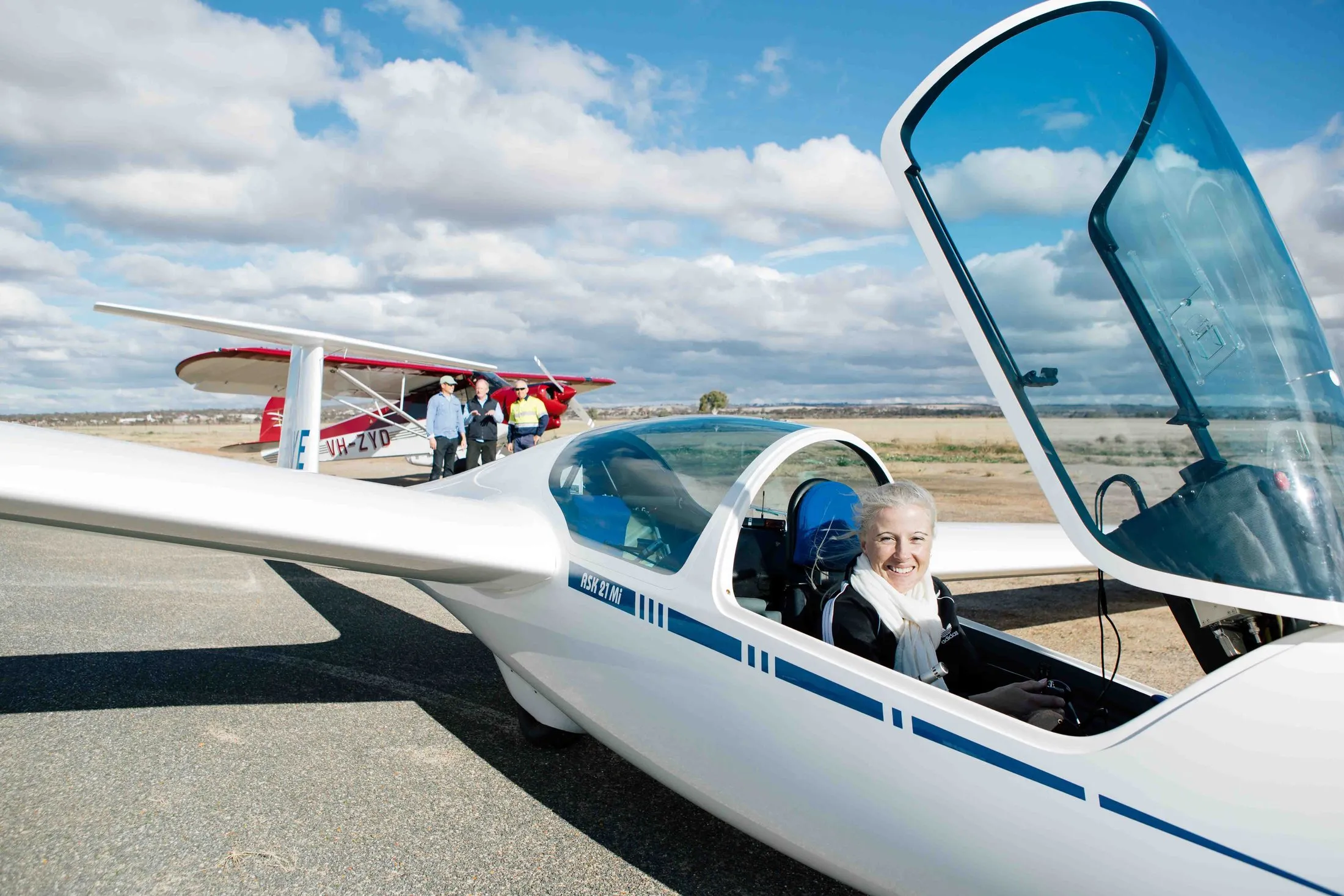 A passenger settled into the glider's front cockpit on the Cunderdin apron, canopy open, visitors watching behind